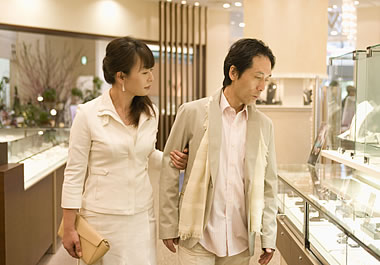 The couple is looking at the jeweler's merchandise.