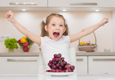 The girl is overly excited about the grapes.