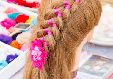 A pink ribbon is intertwined in the girl's hair.