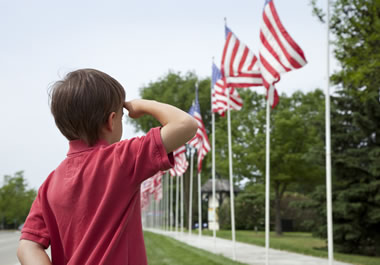 The boy is saluting the American flag.