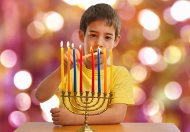 The boy is lighting a Hanukkah menorah.