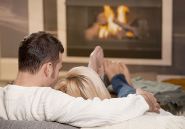 The couple is snuggling by the fire.