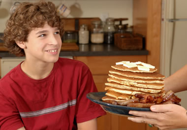 The boy can eat an astounding amount of pancakes.