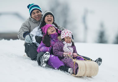 The family is sledding down the hill on a toboggan.