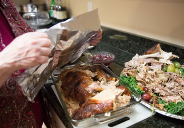The woman is wrapping up the remainder of the turkey.