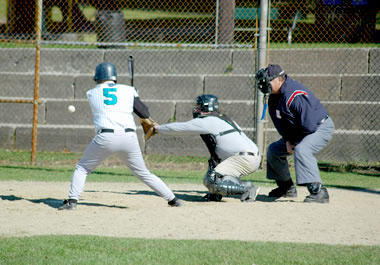 The baseball umpire is positioned behind the catcher.
