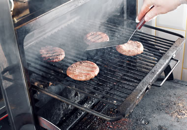 The person is flipping the burgers with a spatula.