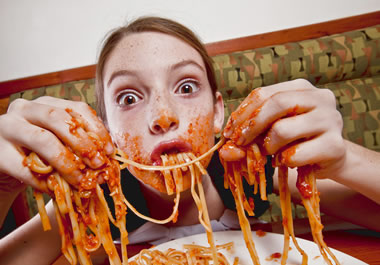 The girl is not following proper etiquette when eating pasta.