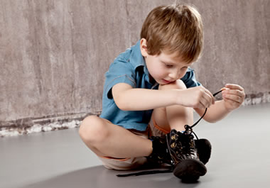 A small boy lacing his shoes
