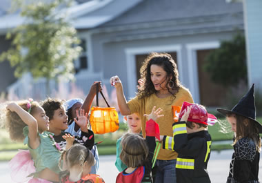 The woman is doling out candy to the children.