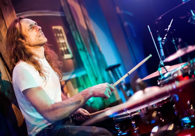 An old-style rocker playing the drums in a rock band