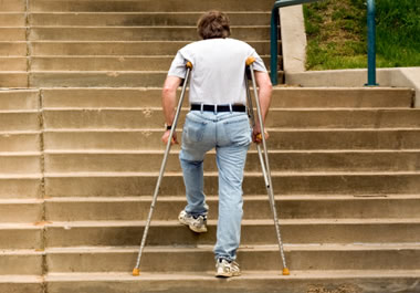 Man walking up stairs on crutches