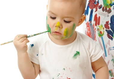 A baby smearing paint on her face