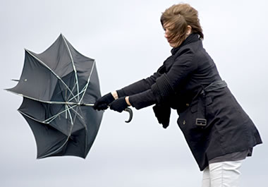 Woman struggling to close an umbrella