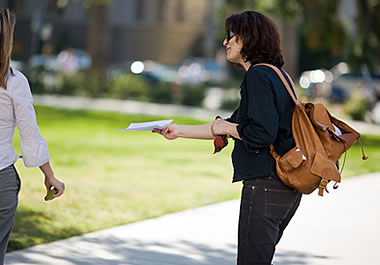 A woman handing out fliers in a park