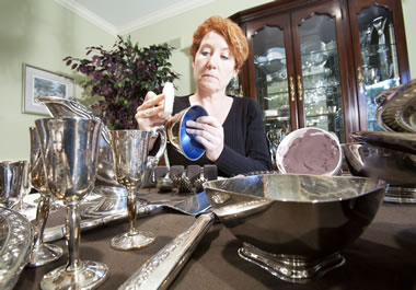 The woman is polishing the silver to restore its luster.