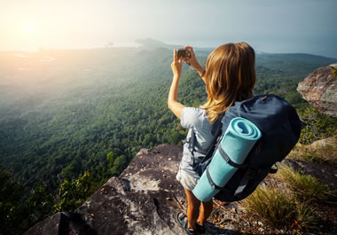 The woman is enamored with the view from the mountaintop.