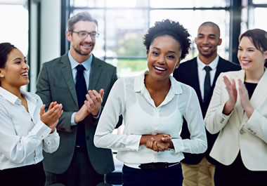 The woman's coworkers are applauding her accomplishment.