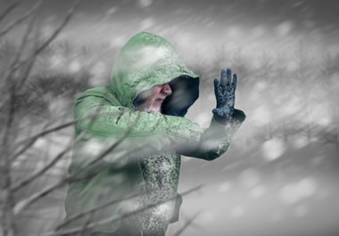 The man is protecting his face from the frigid wind.