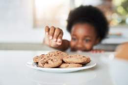 child reaching for a plate of cookies