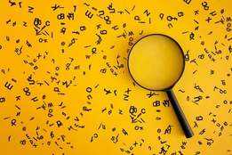magnifying glass on yellow background surrounded by letters