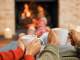 couple drinking mugs of hot chocolate in front of a fireplace