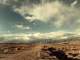 ufo spaceship hovering over a desert road with puffy clouds