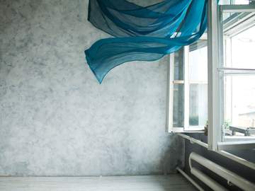 an open window with aqua colored curtains blowing in the breeze