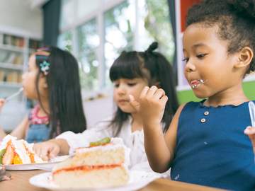 girls sitting at a table eating cake