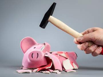 hand with hammer smashing piggy bank