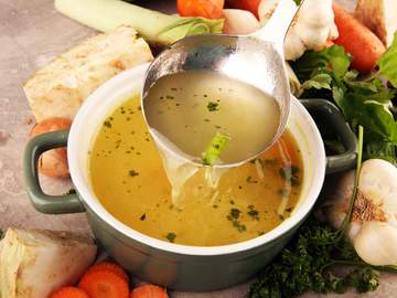 ladle dipping into a bowl of broth or stock