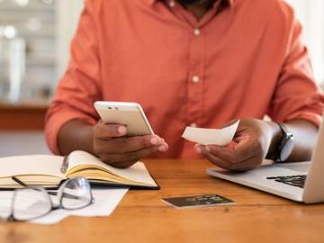 man hands using smartphone and holding receipt
