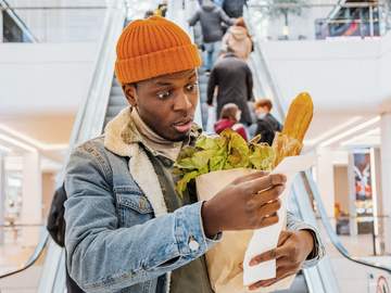 man looks at groceries receipt in shock