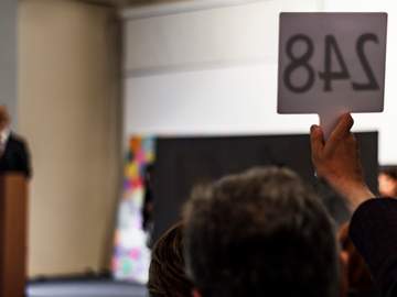 person holding up placard at auction