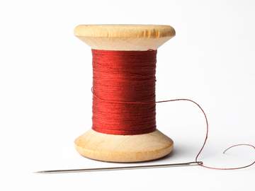 spool of red thread with a needle