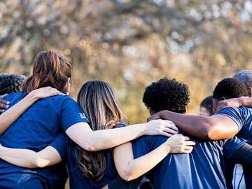 team of people with arms linked on shoulders