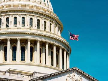 the united states capitol dome with flag flying in foreground