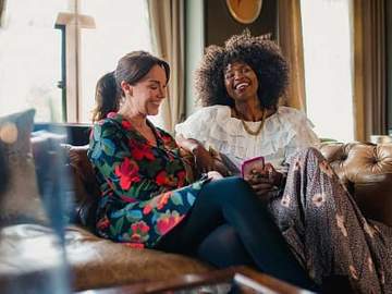 two women sitting on a couch and smiling