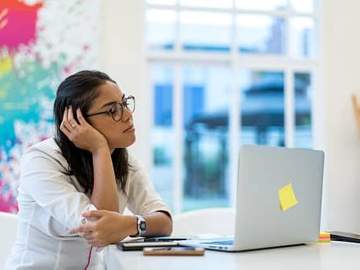 woman sitting at computer looking bored