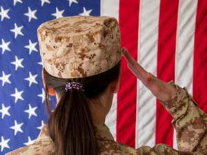 soldier seen from behind saluting flag