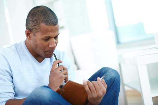 man pensively writing in book