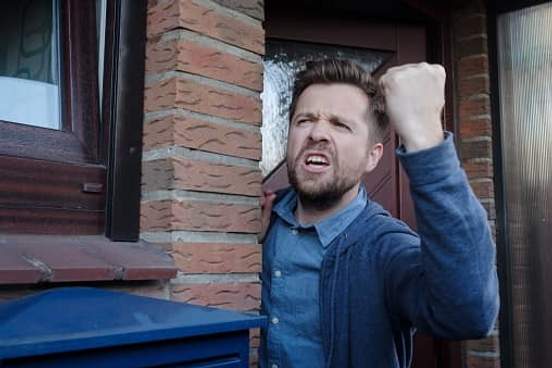 man shaking fist out front door