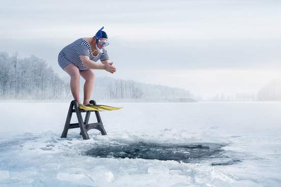 man with snorkle on about to dive into icy lake