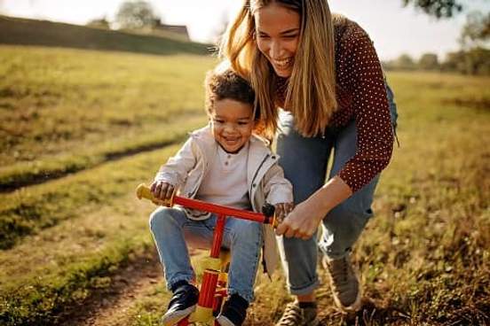 woman helping son on bike