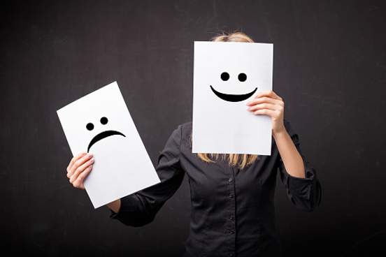 woman holding smiley face paper up