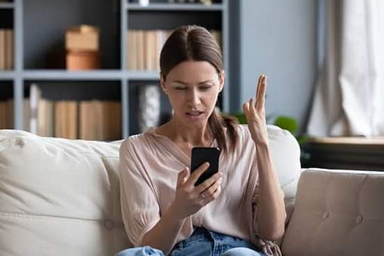 woman looking at phone and being annoyed