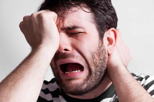 despairing man rubbing his face