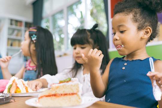 girls sitting at a table eating cake