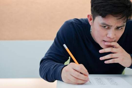 high school student holding a pencil leaning over a sat test