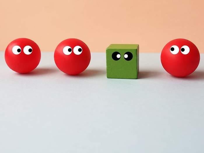 image of a green cube out of place in a lineup of red spheres 